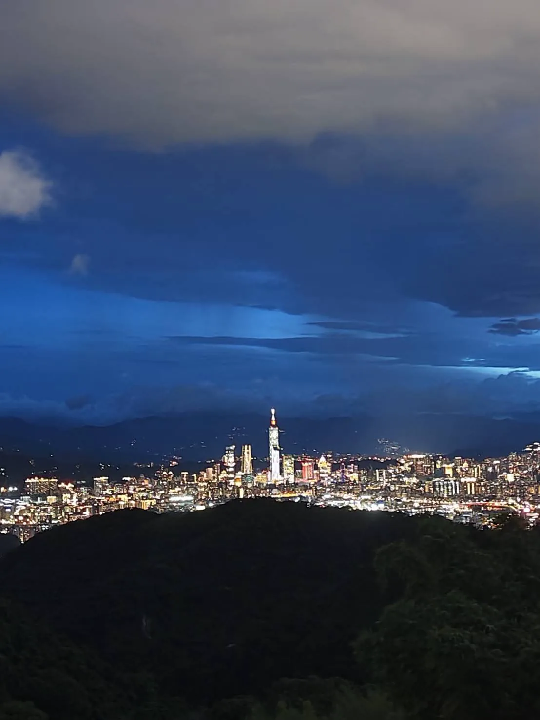 從黃氏古厝所在處拍攝的夜景，深色山影前方可見台北城市燈光與雲層